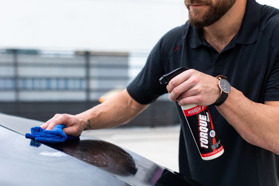 Close-up of a detailer hand-waxing a car panel to a mirror finish